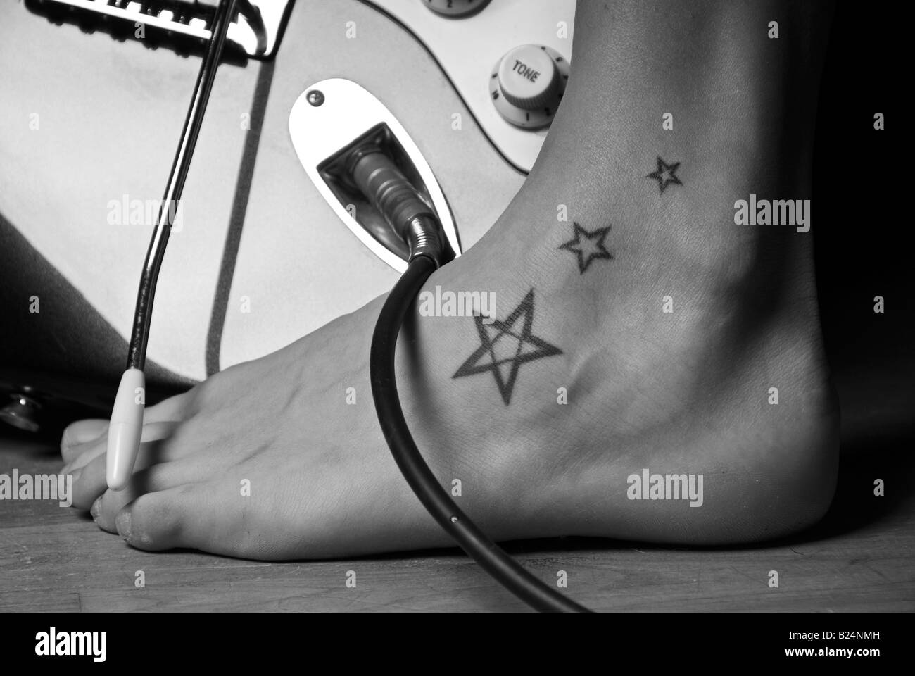 Stock photo d'une jeune femme avec trois pieds tatouages étoiles à côté d'une guitare électrique Banque D'Images