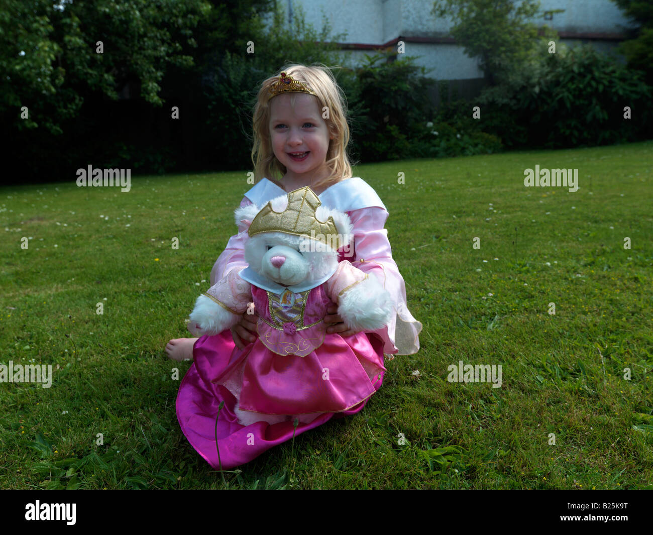 Fille habillée comme princesse avec un ours de princesse dedans A Garden Surrey Angleterre Banque D'Images