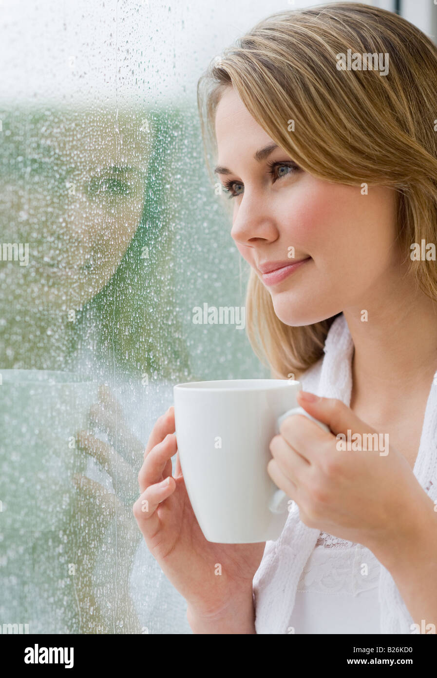 Femme regardant par la fenêtre la pluie Banque D'Images