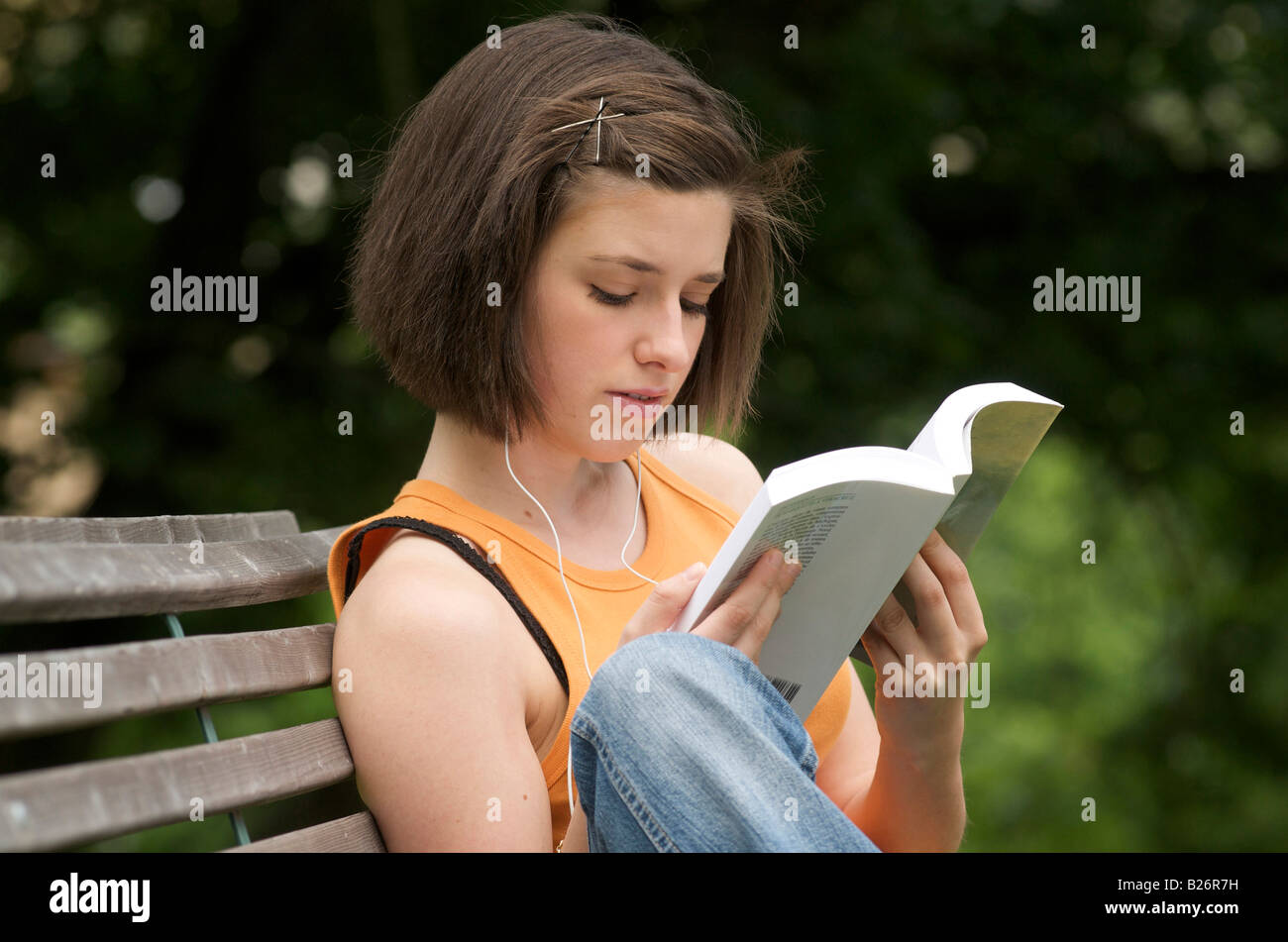 Jeune femme / adolescent lisant dans un parc Banque D'Images