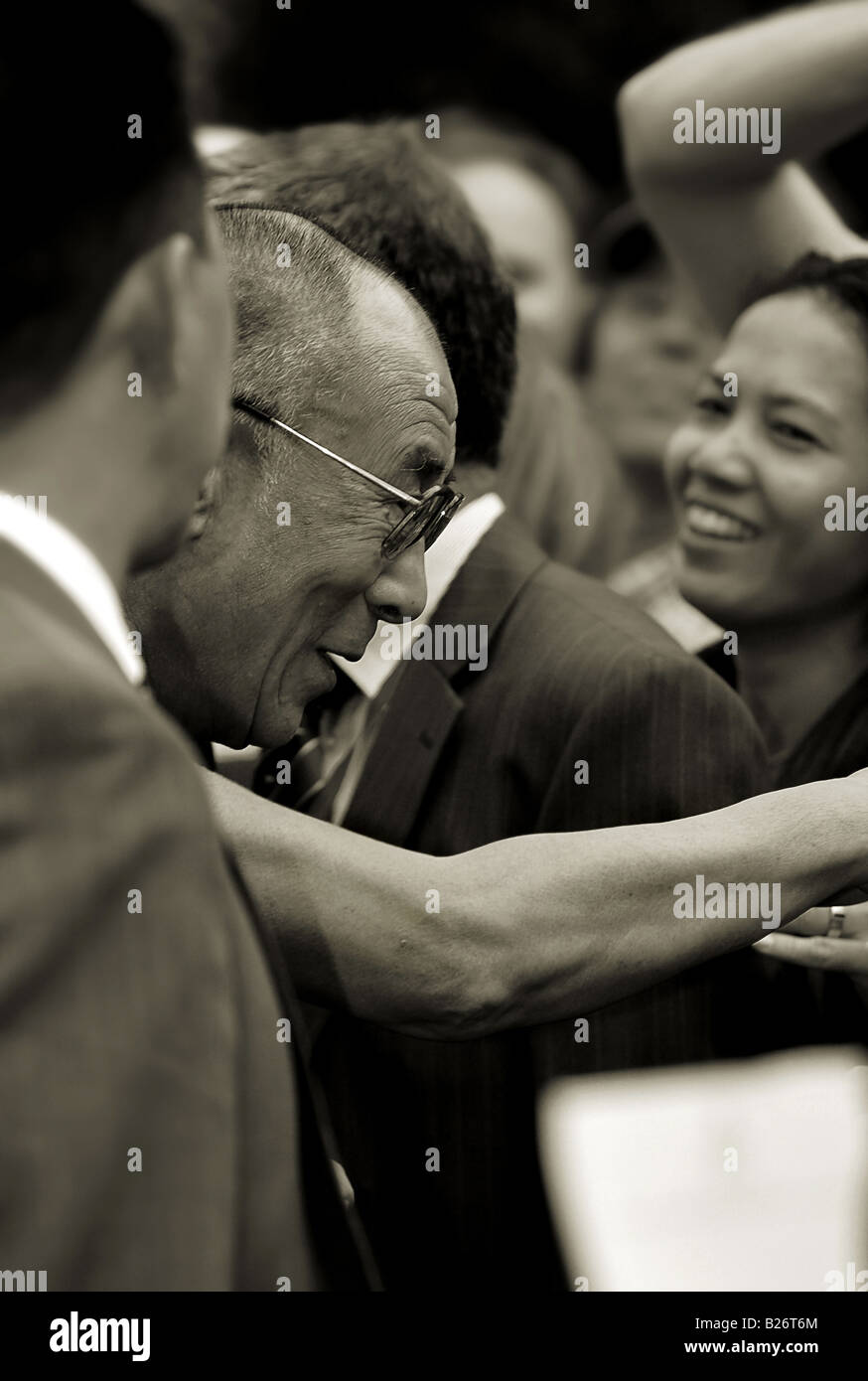 - Sa Sainteté Tenzin Gyatso, le quatorzième Dalaï-lama en souriant et serrant la main dans une foule joyeuse Banque D'Images