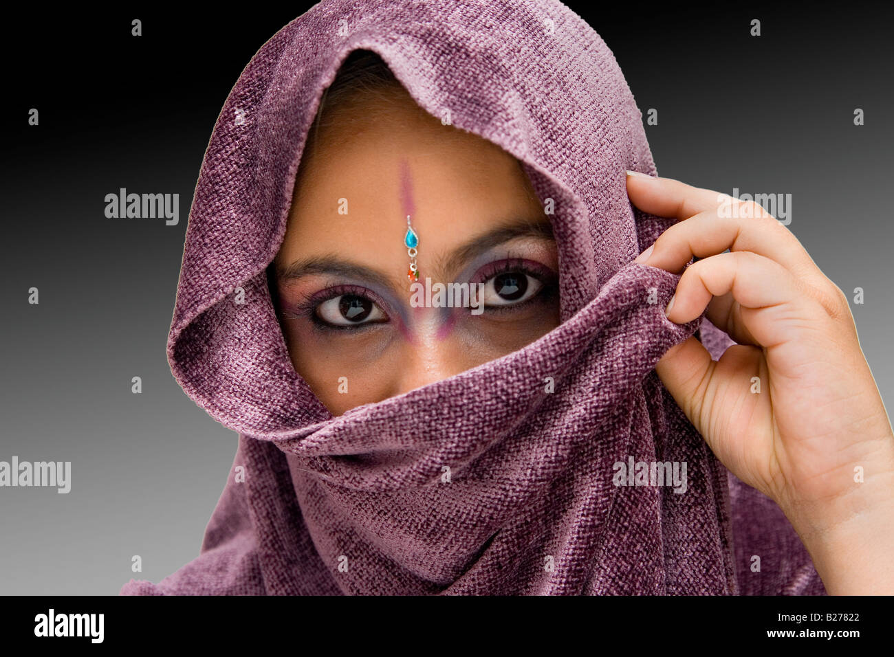 Jeune femme hindoue avec comme un miroir et écharpe pourpre avec un regard  pénétrant isolé sur un gradient de gris foncé à noir Photo Stock - Alamy
