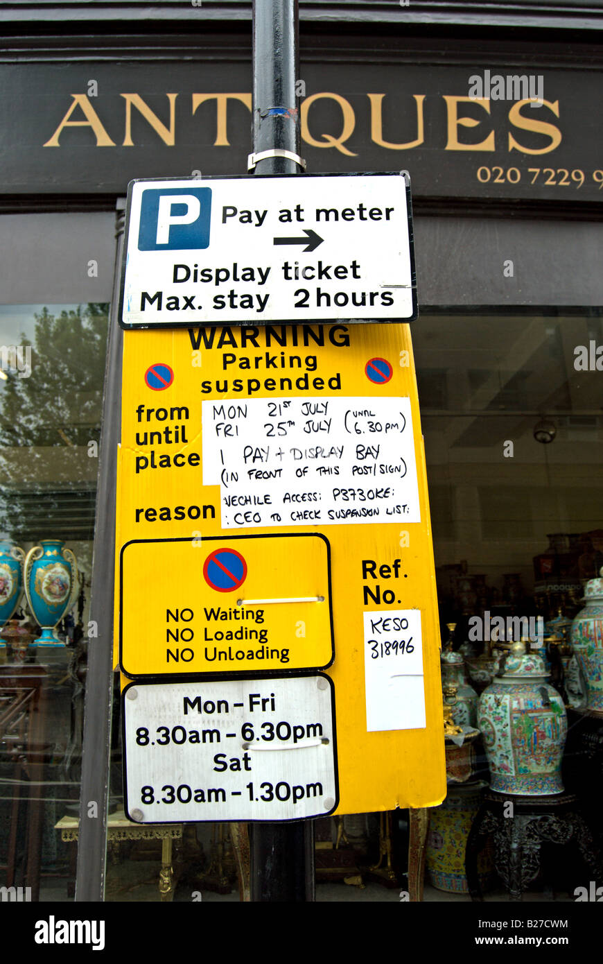 Des signes britannique encombré avec les règlements et les restrictions de stationnement à l'extérieur d'un magasin d'antiquités à Kensington, à l'ouest de Londres, Angleterre Banque D'Images