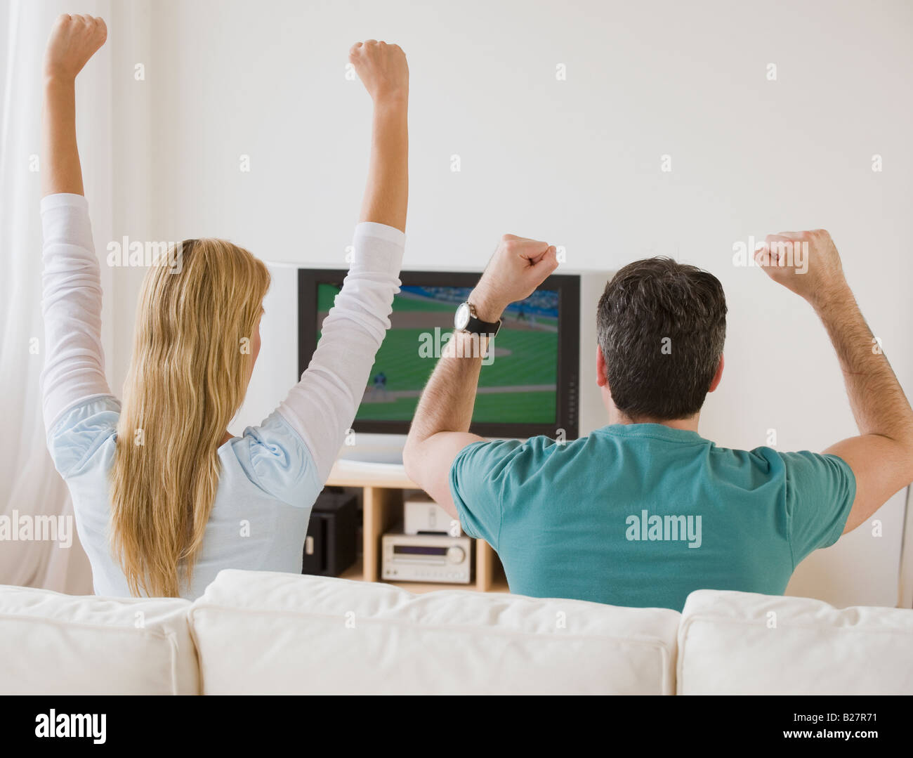 Couple cheering at television Banque D'Images