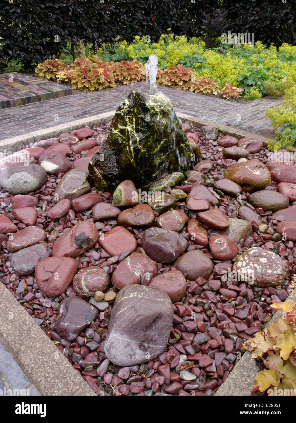 Fontaine en pierre avec jardin de vivaces Banque D'Images