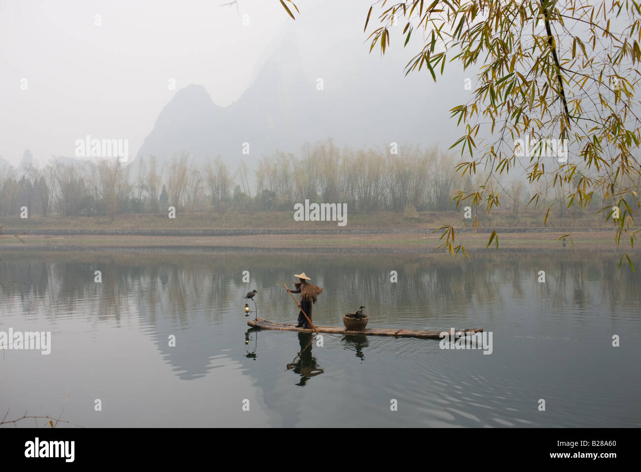 Pêcheur dans Suoyi manteau et coolie hat fishes avec cormorans sur Li River près de Guilin Chine Banque D'Images