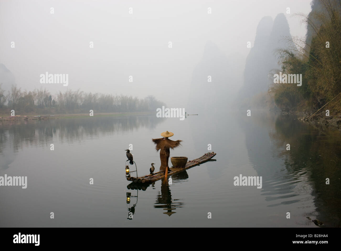 Pêcheur dans Suoyi manteau et coolie hat fishes avec cormorans sur Li River près de Guilin Chine Banque D'Images