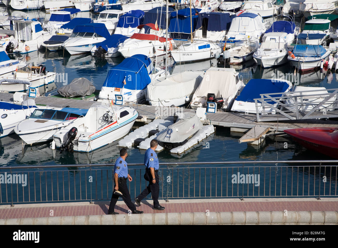 Deux policiers contrôler bateaux amarrés et yachts dans le port de plaisance de Puerto Rico Gran Canaria Espagne Banque D'Images