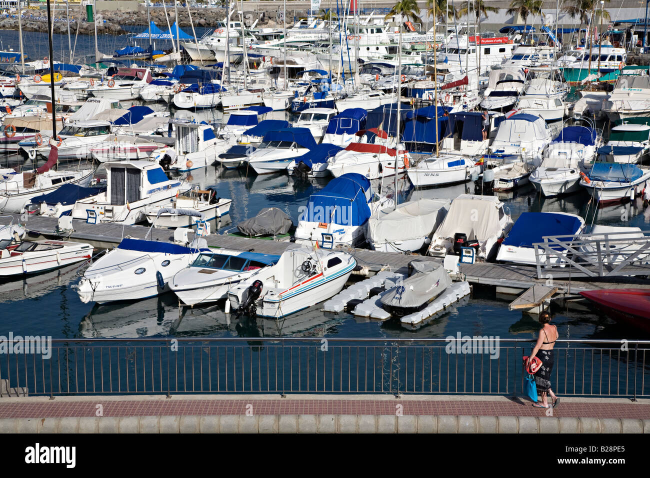 Femme regardant les bateaux et yachts amarrés dans le port de plaisance de Puerto Rico Gran Canaria Espagne Banque D'Images