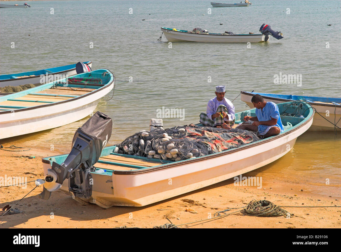 Deux pêcheurs réparer leurs filets en bateau à Al Ayjah près de Sur Oman Banque D'Images