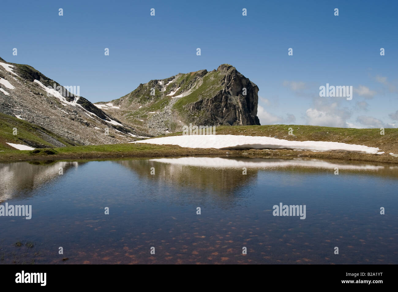 Petit lac alpin et la fonte des plaques de neige sous roche de mio Banque D'Images