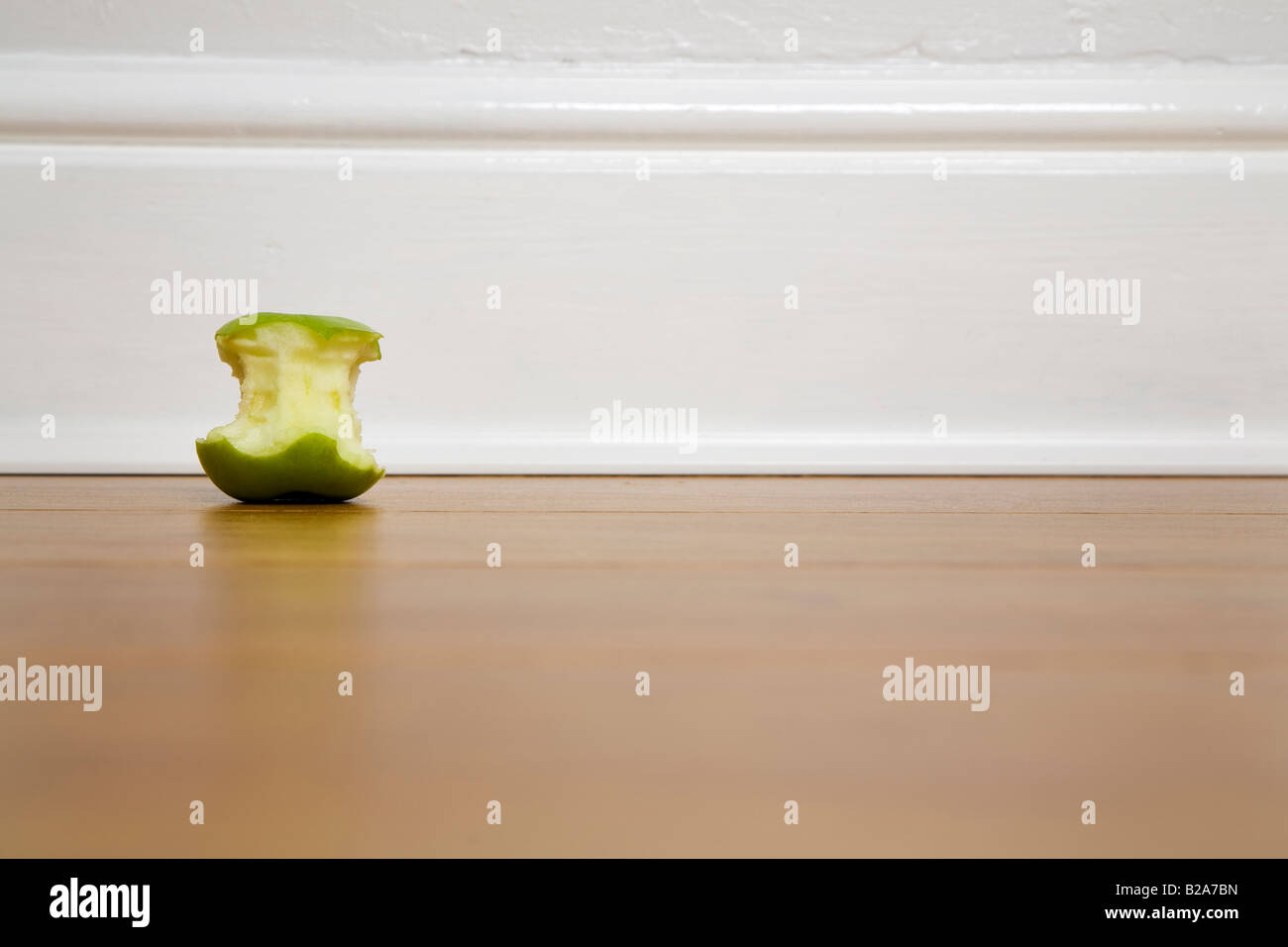 Mangé une pomme verte tourné contre une plinthe blanc Banque D'Images