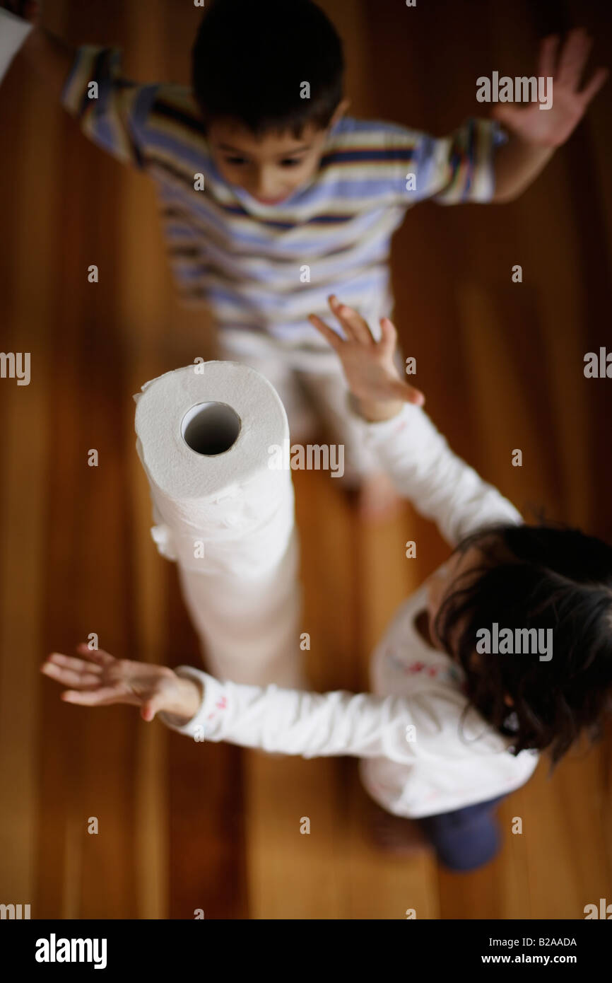 Les enfants à construire tour de rouleaux de papier toilette garçon âgés de six et cinq sœurs mixed race caucasienne et ethnique indien Banque D'Images