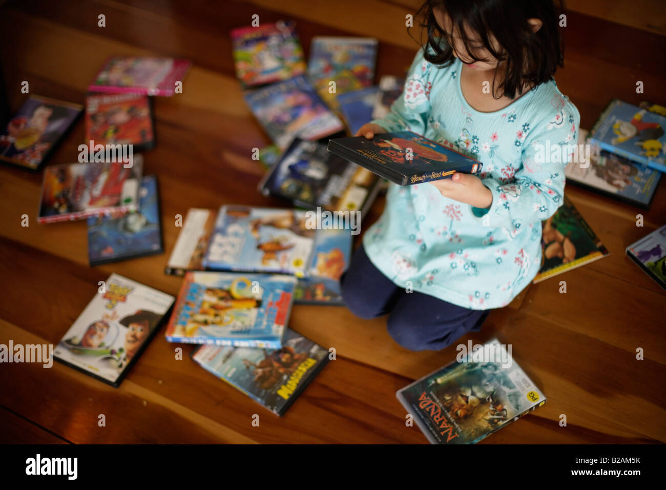 Petite fille de cinq ans passe du temps le choix d'un DVD pour regarder dans l'après-midi Banque D'Images