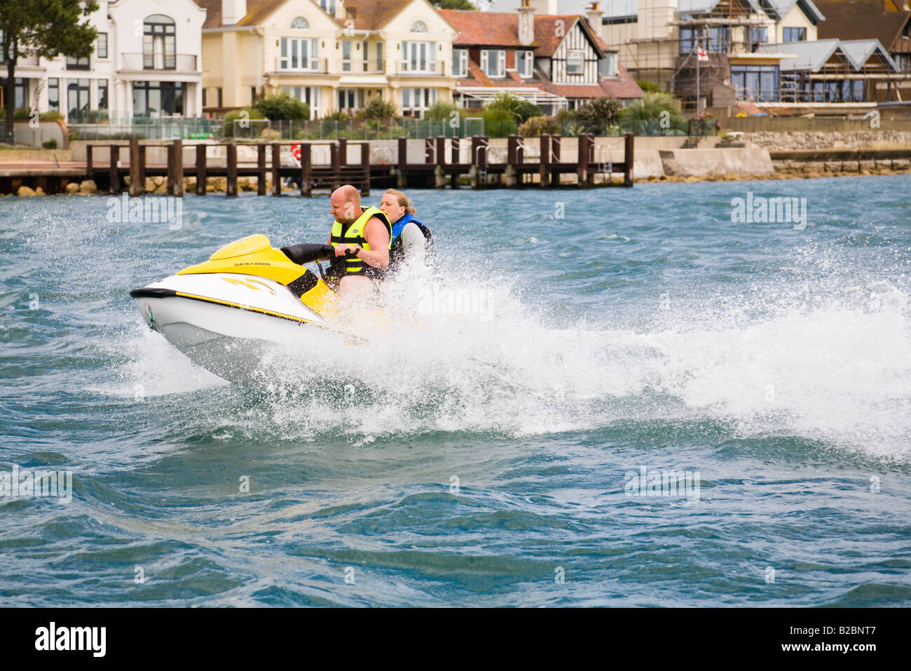 Les gens jet ski en face de la mer à propriétés coûteuses, Sandbanks Poole, Dorset. UK Banque D'Images