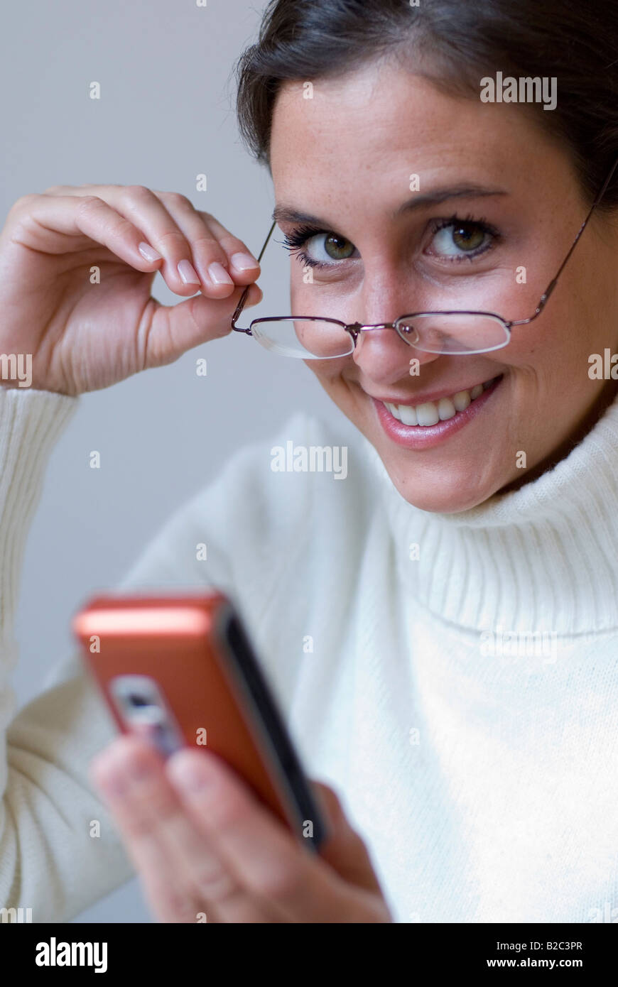 Jolie jeune femme avec des lunettes sur le bout de son nez, l'envoi de sms Banque D'Images Jolie jeune femme avec des lunettes sur le bout de son nez, l'envoi de sms Banque D'Images