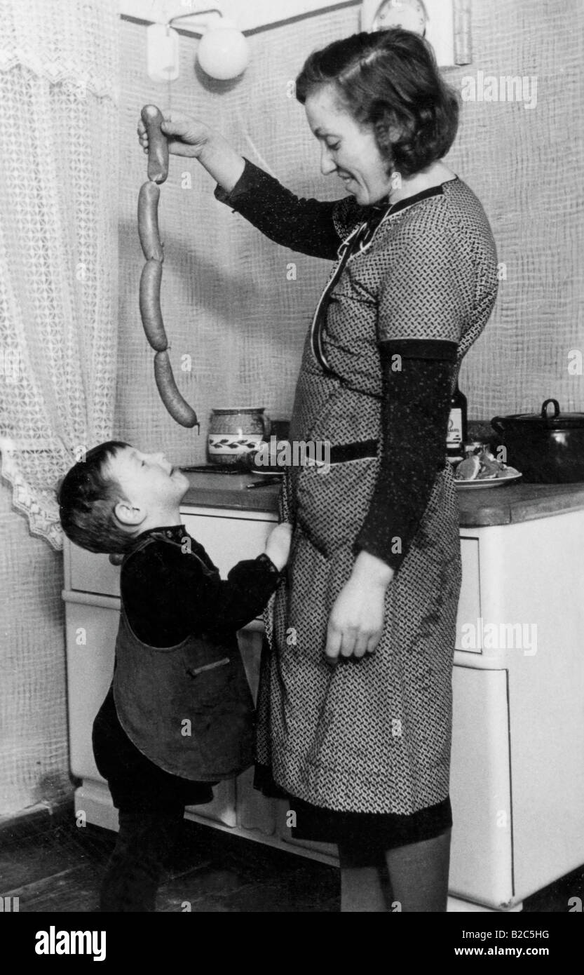 Mère se moque de garçon avec des saucisses, des photos historiques, vers 1940 Banque D'Images