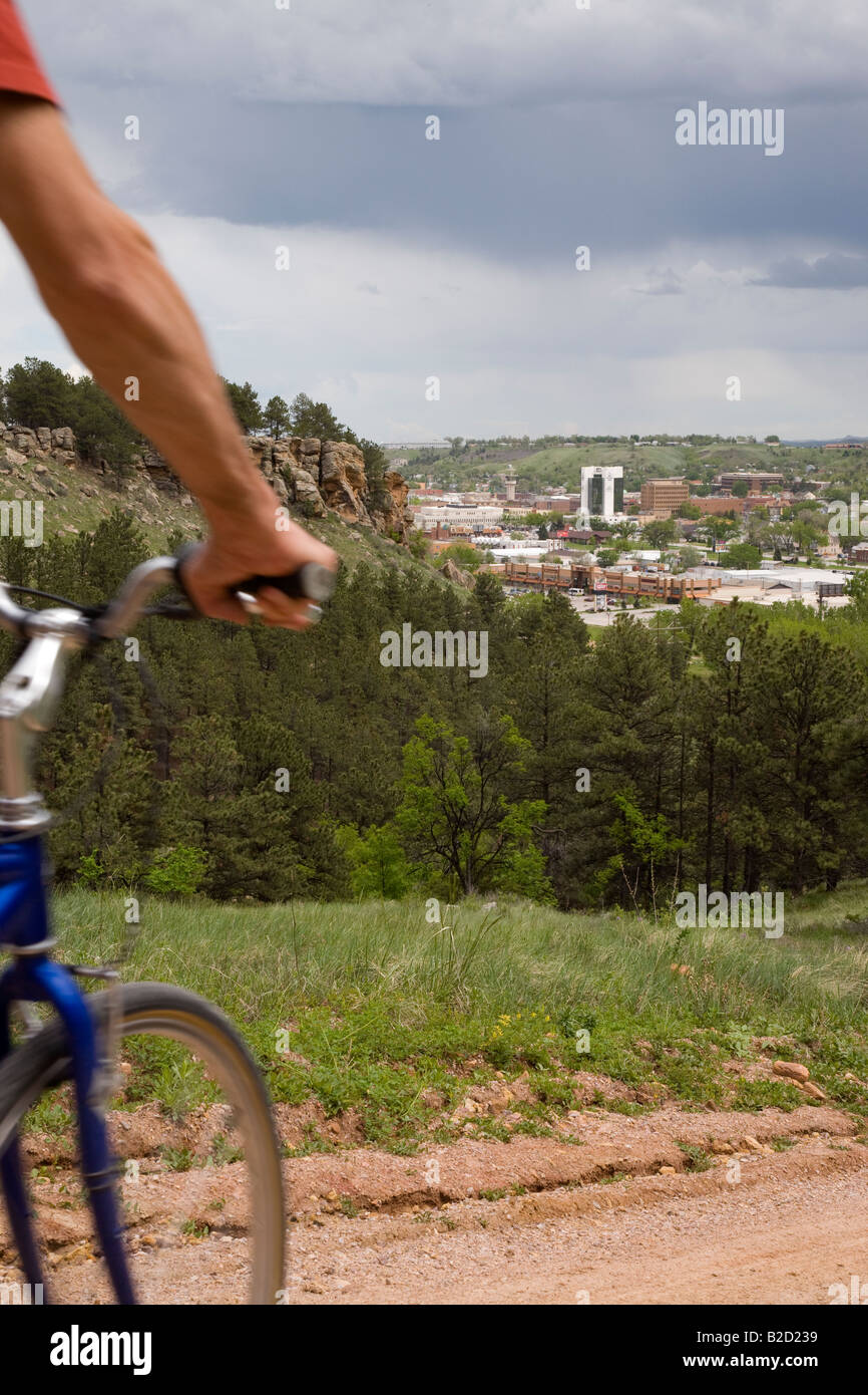 Cycliste sur M Hill (alias Cowboy Hill) avec le centre-ville de Rapid City dans la distance, Chuck Lien Family Park, Dakota du Sud Banque D'Images