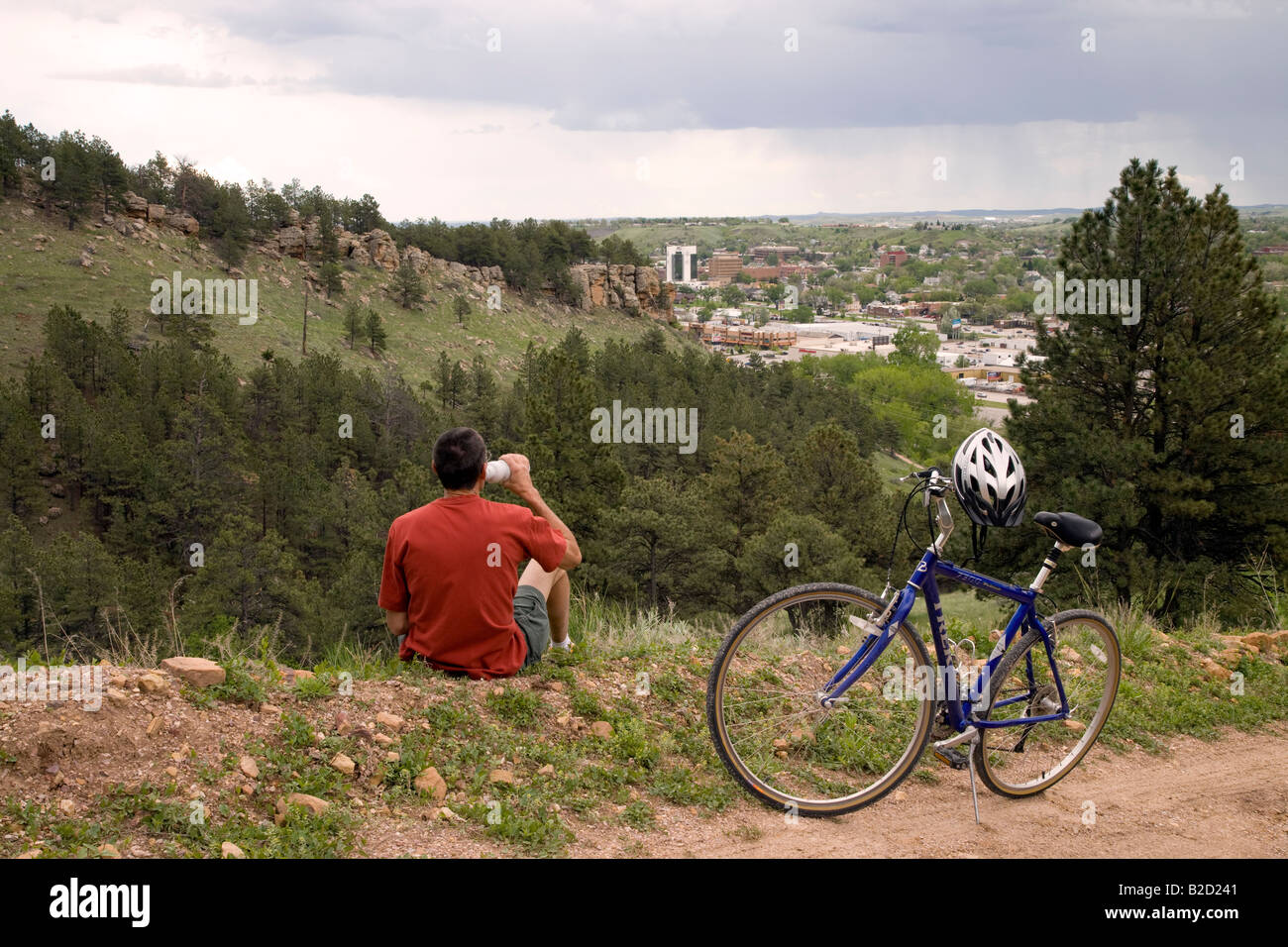 Cycliste sur M Hill (alias Cowboy Hill) avec le centre-ville de Rapid City dans la distance, Chuck Lien Family Park, Dakota du Sud Banque D'Images