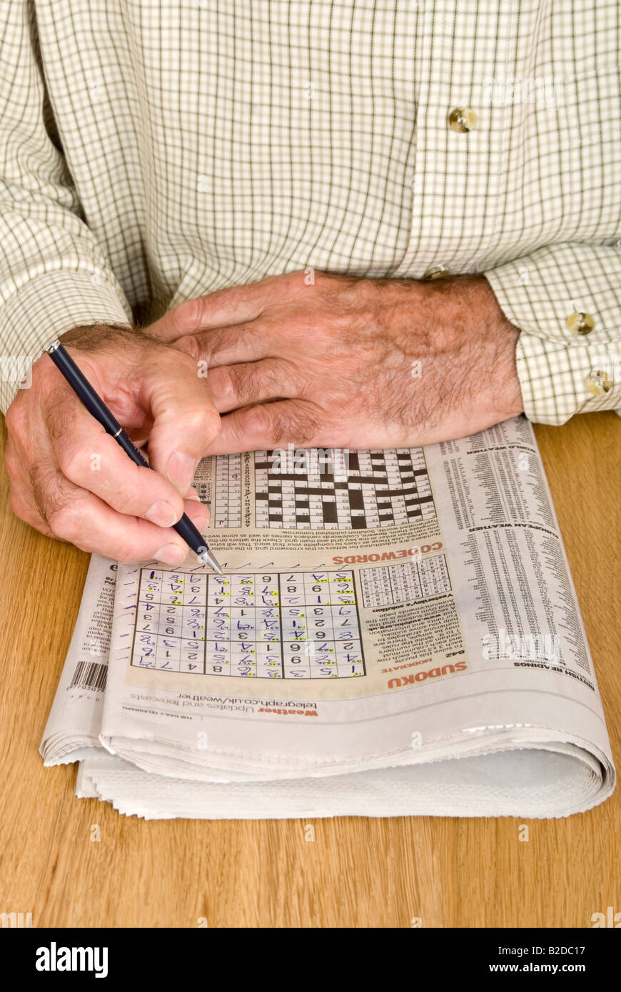 Portrait vertical d'un vieux monsieur de faire le puzzle Sudoku dans son quotidien Banque D'Images