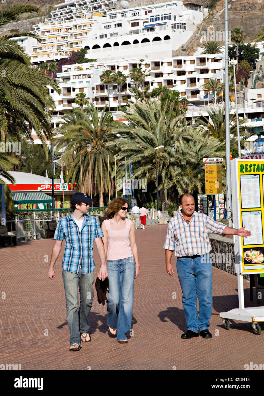 Vantant l'homme d'affaires de couple demande de venir dans son restaurant à tourist resort Puerto Rico Gran Canaria Espagne Banque D'Images