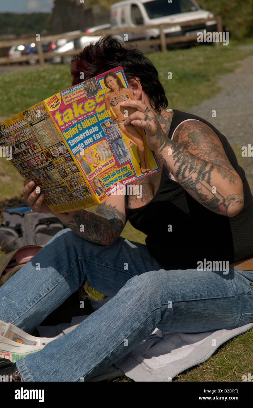 Femme tatouée fortement prendre lecture hebdomadaire5 UK magazine vie potins de cacher son visage de l'appareil photo Banque D'Images