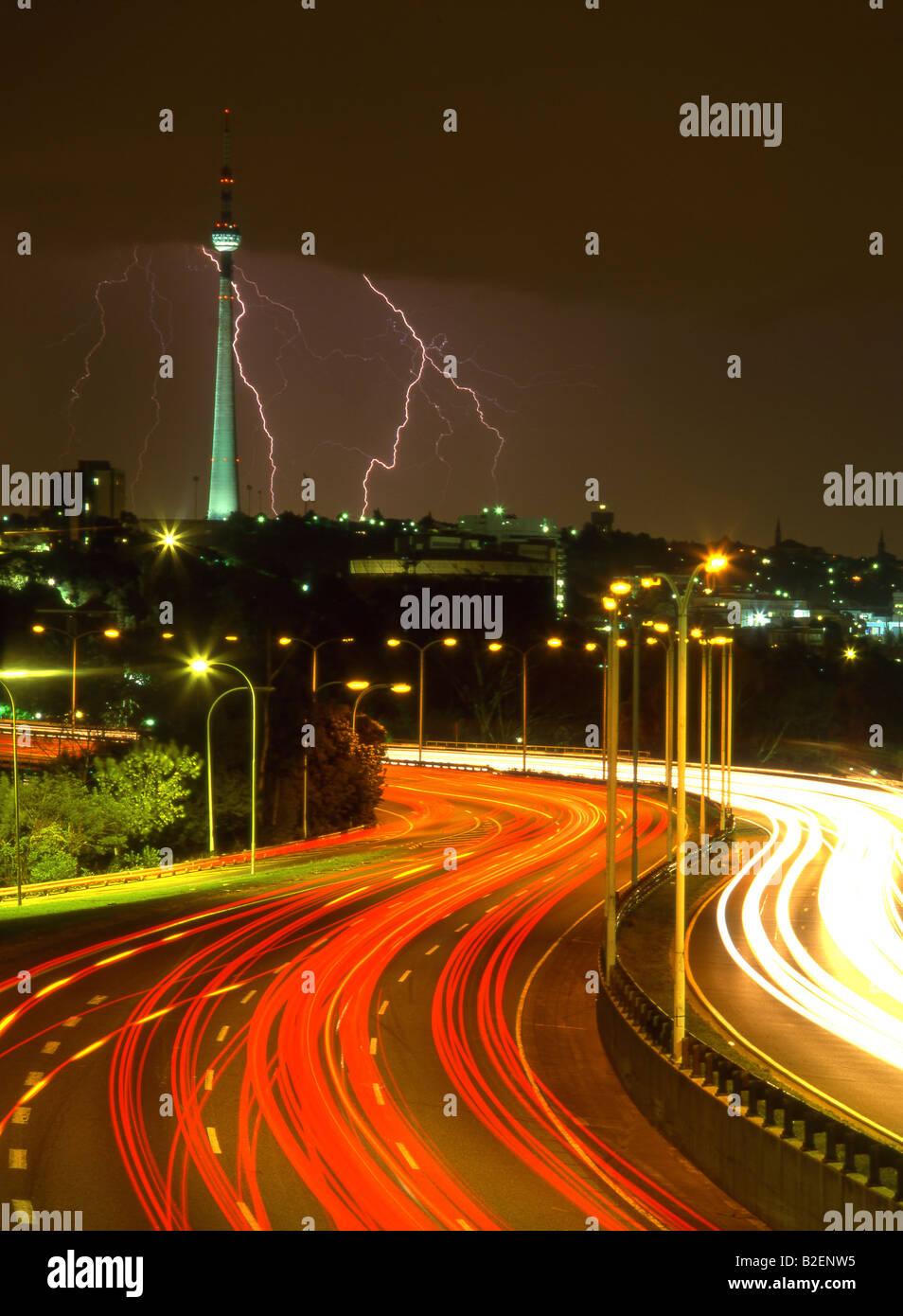 Les sentiers de la lumière des voitures qui se déplacent le long de l'autoroute à Johannesburg une nuit avec la foudre autour de la tour de Brixton Banque D'Images