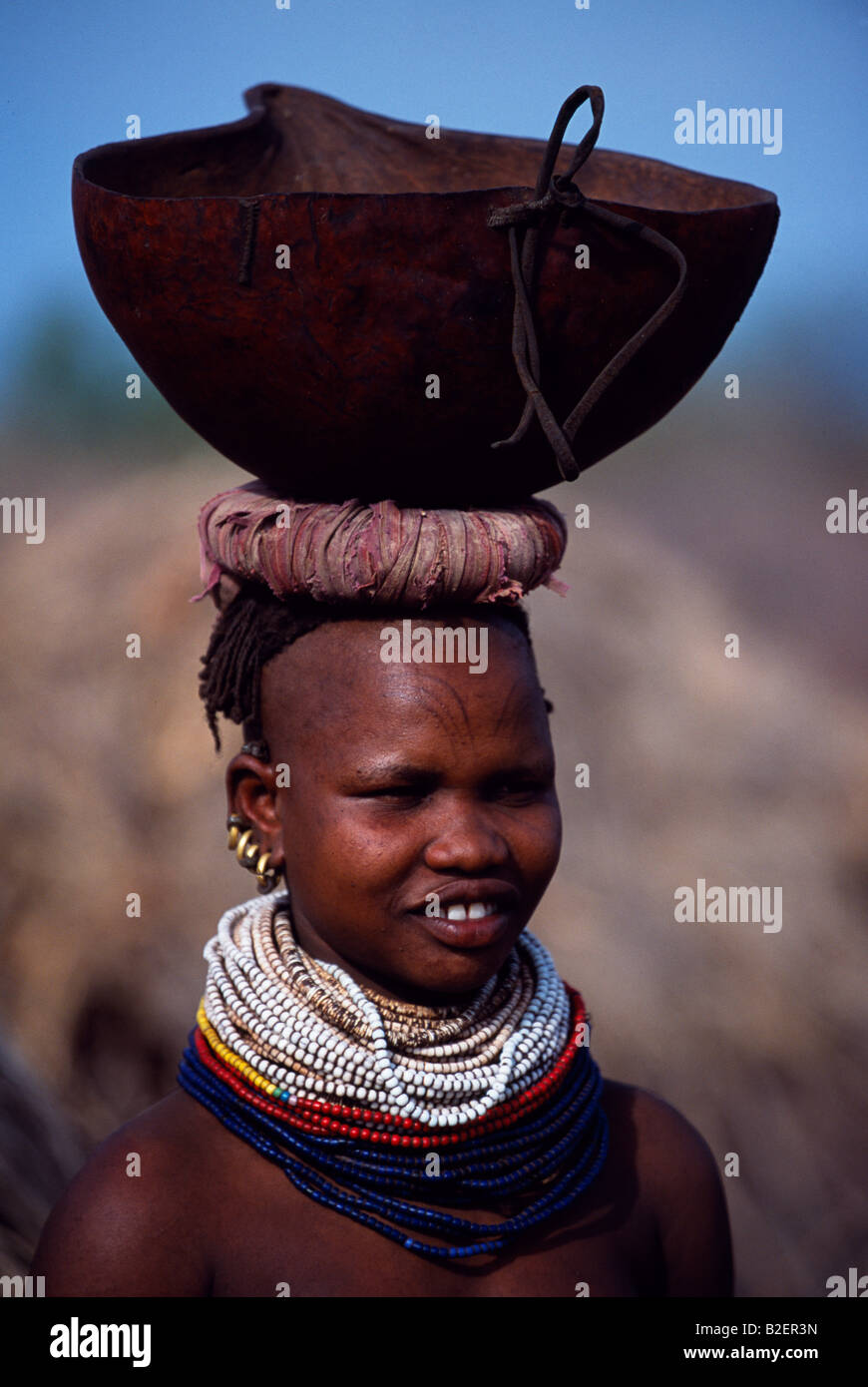 Une femme porte une gourde Nyangatom sur sa tête. Typique de sa tribu, elle porte ses cheveux en tresses. Banque D'Images