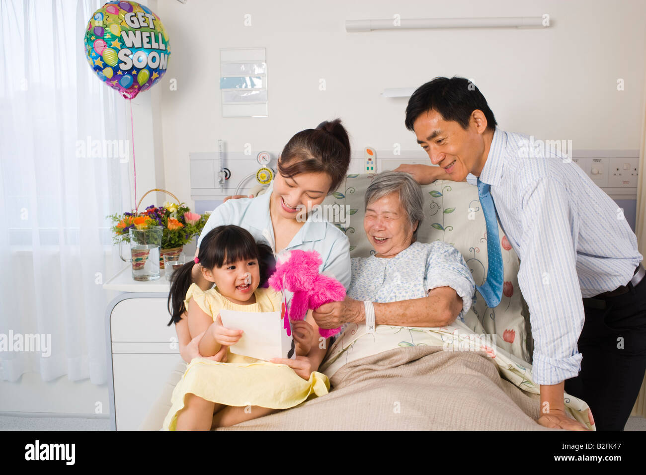 Femme couchée sur le lit et souriant avec sa famille à côté d'elle Banque D'Images