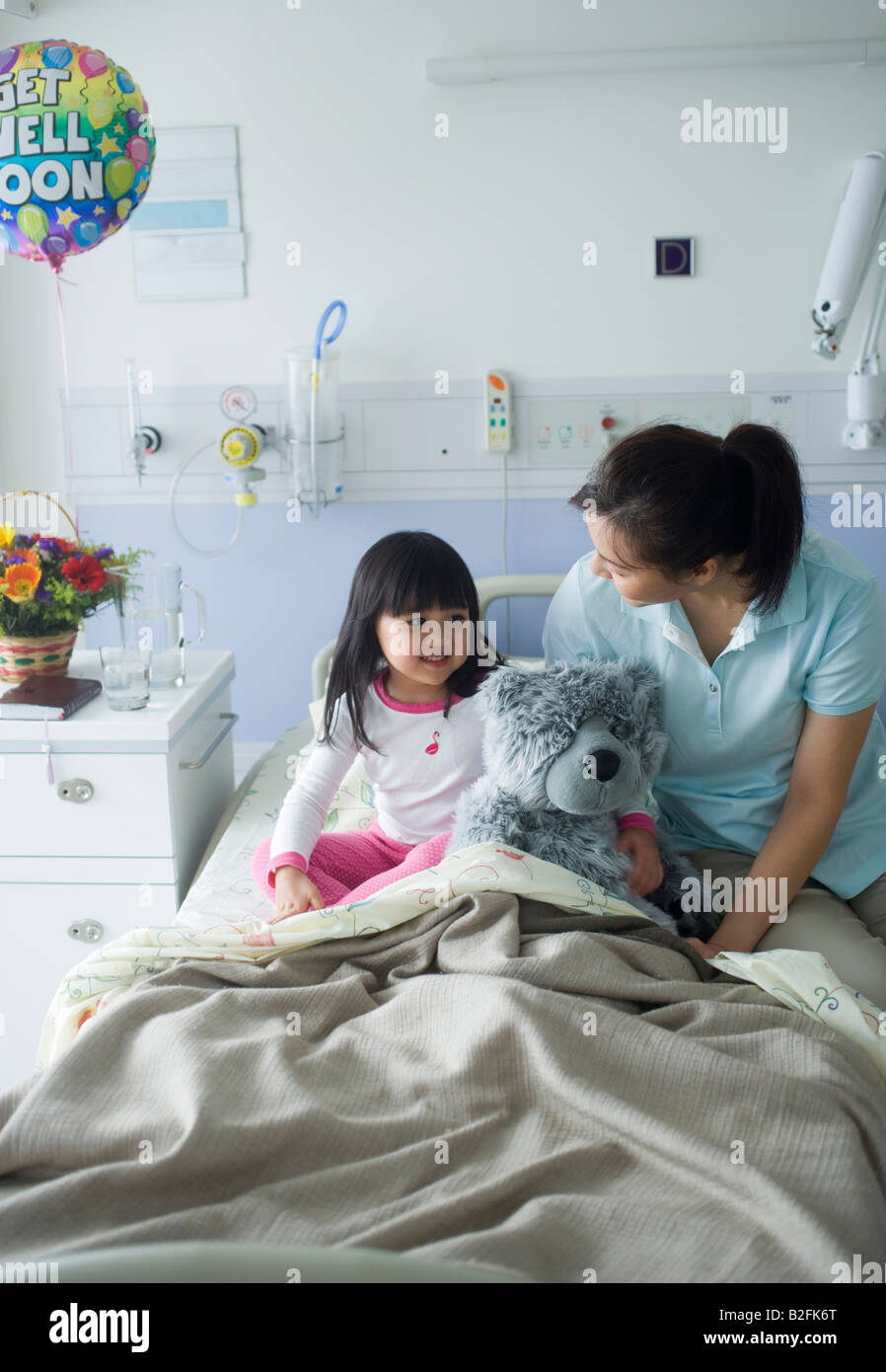 High angle view of a Mid adult woman assis sur le lit avec sa fille dans un hôpital Banque D'Images