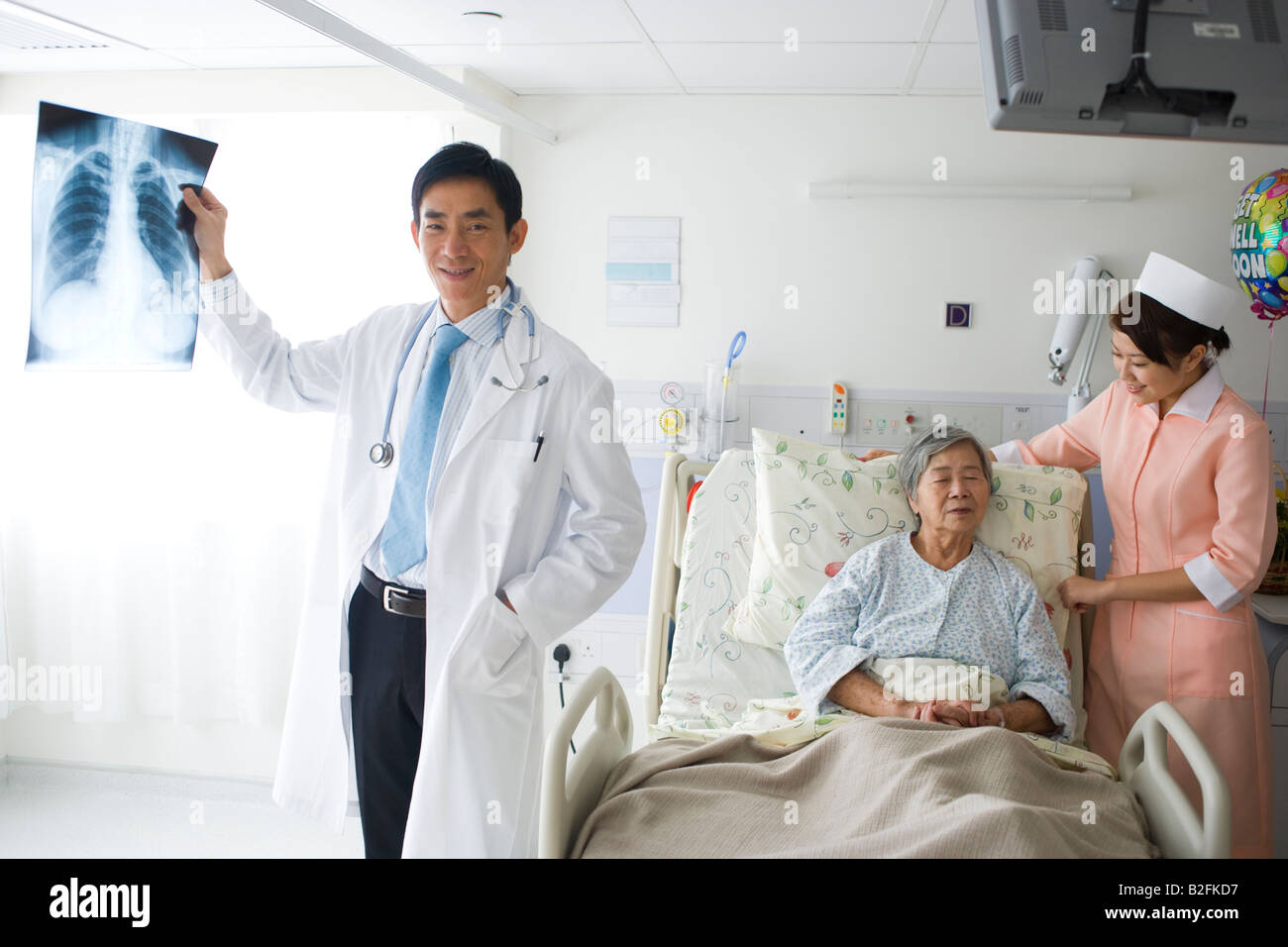 Médecin homme tenant un rapport des rayons X avec un patient et une infirmière derrière lui Banque D'Images