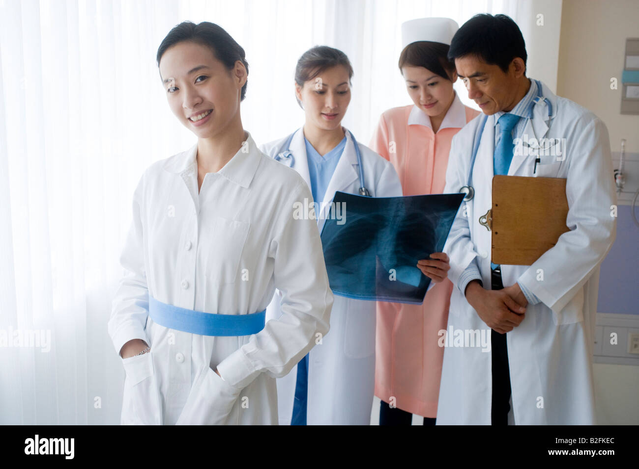 Portrait of a female nurse smiling avec d'autres médecins l'examen d'une X-Ray report en arrière-plan Banque D'Images