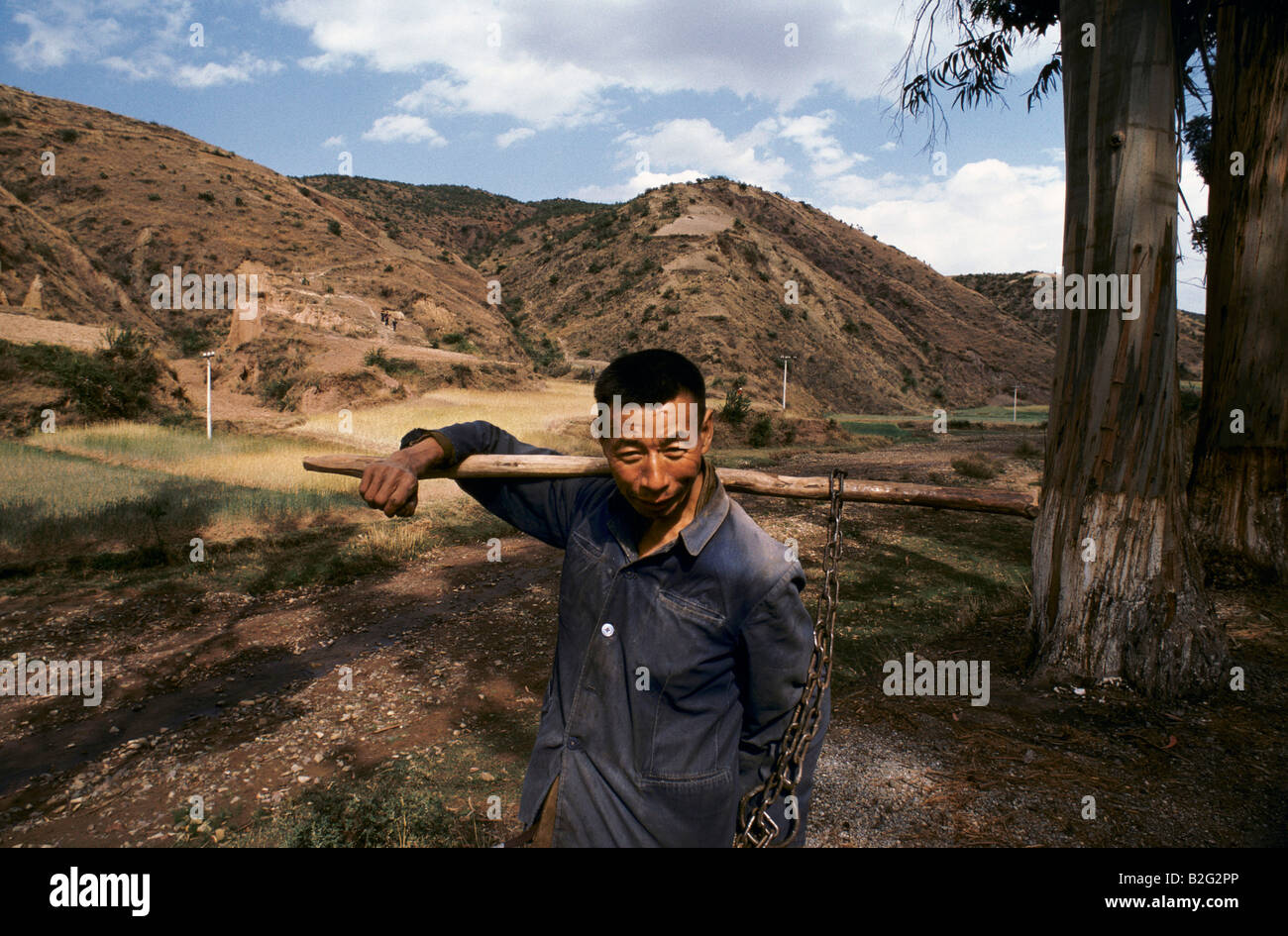 Un homme tenant des outils agricoles en Chine rurale Banque D'Images