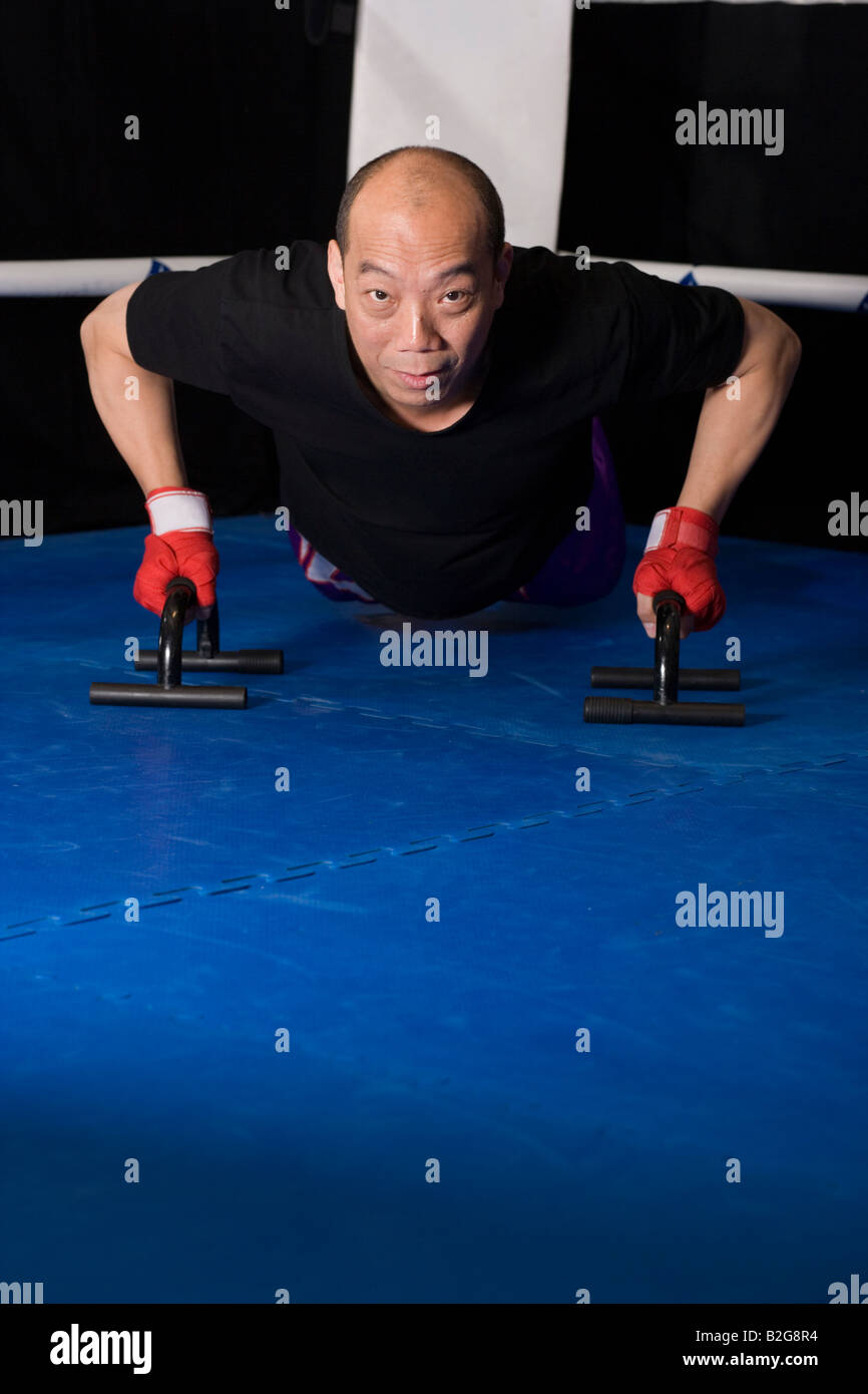 Man exercising with push-up bars dans un ring de boxe Banque D'Images