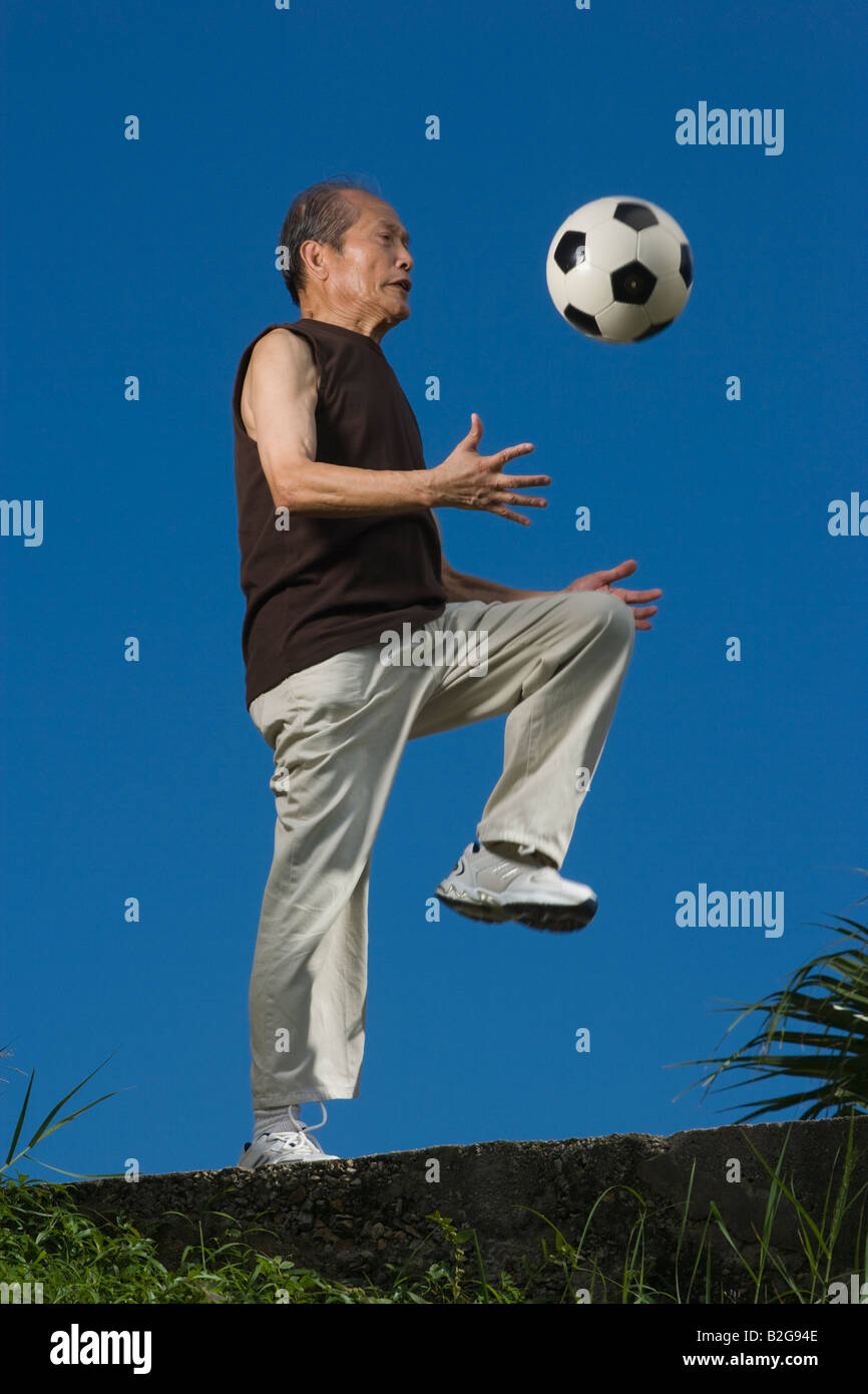 Low angle view of a senior man jouer avec un ballon de foot Banque D'Images