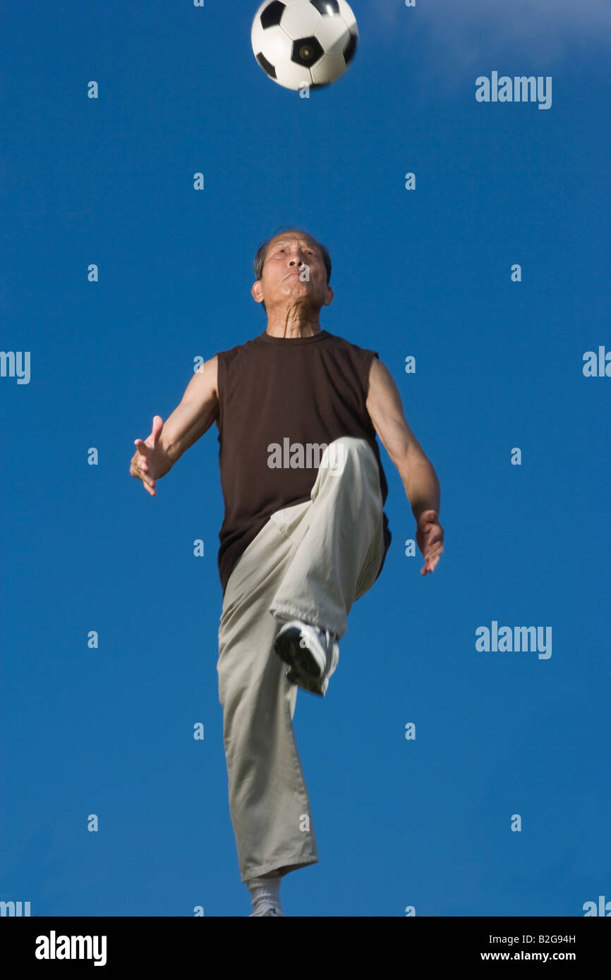 Low angle view of a senior man jouer avec un ballon de foot Banque D'Images