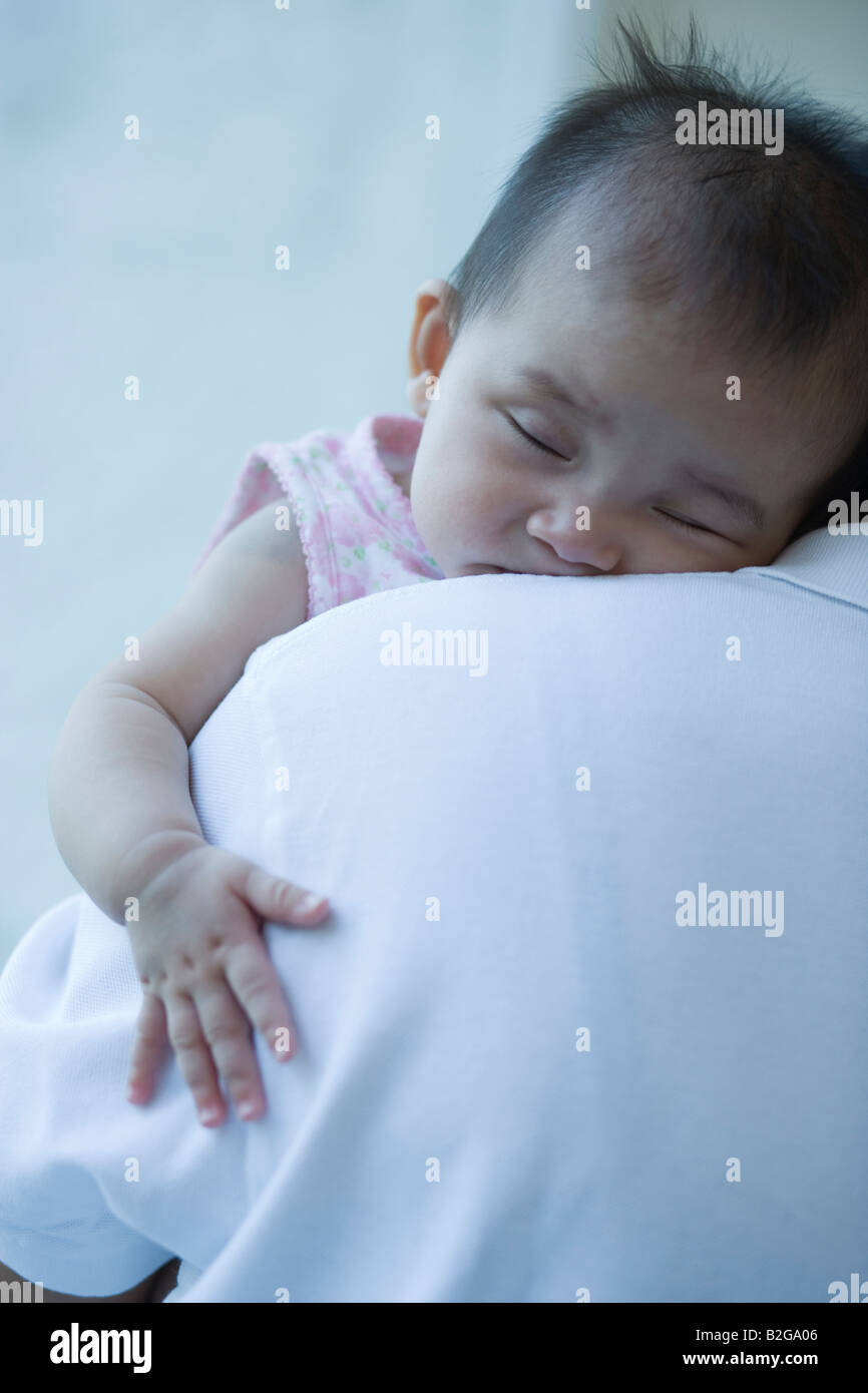 Close-up of a baby girl sleeping sur l'épaule de son père Banque D'Images