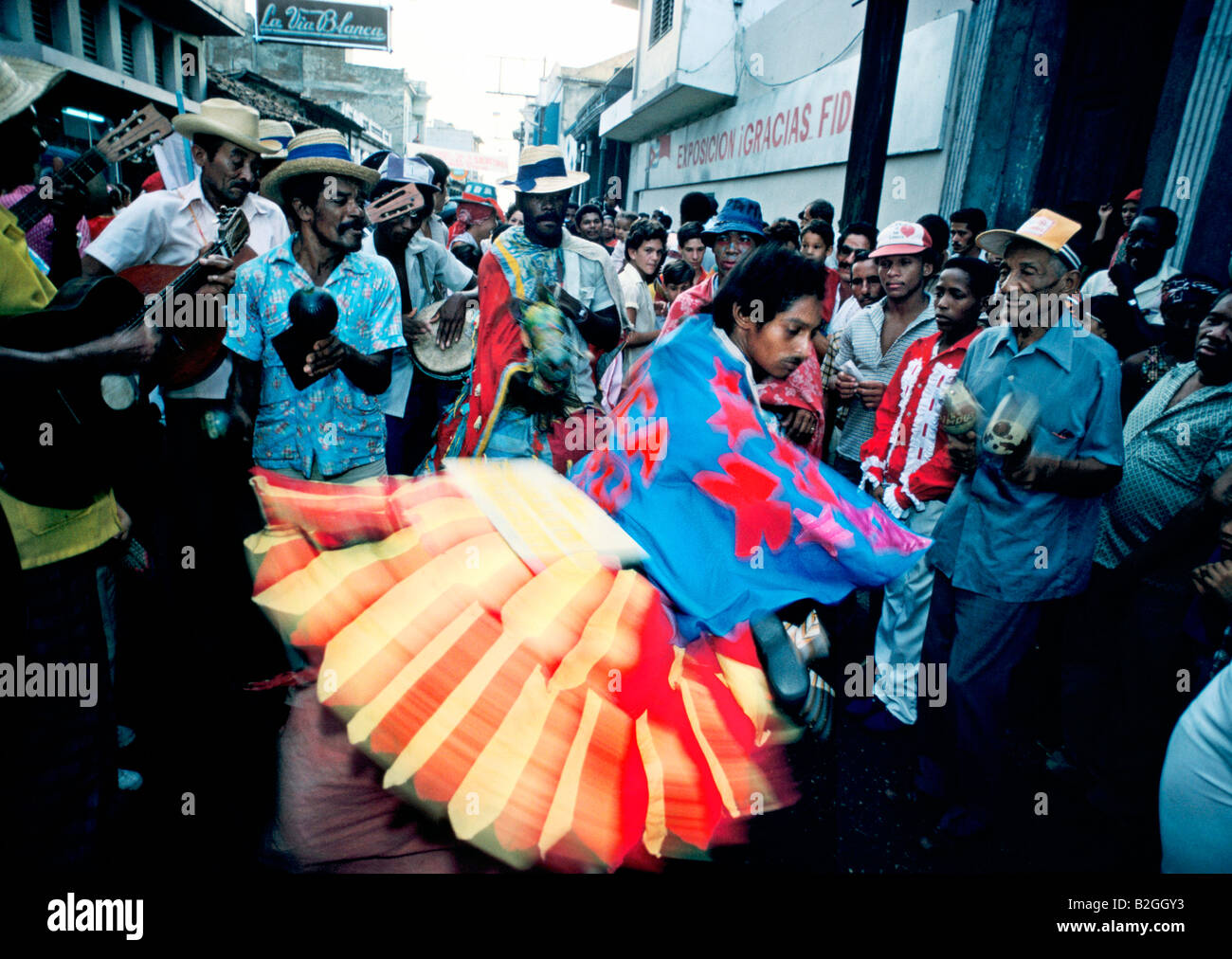 Homme de danse à la musique des joueurs de guitare traditionnelle portant une jupe évasée à l'Santiago carnaval de rue, Cuba Banque D'Images