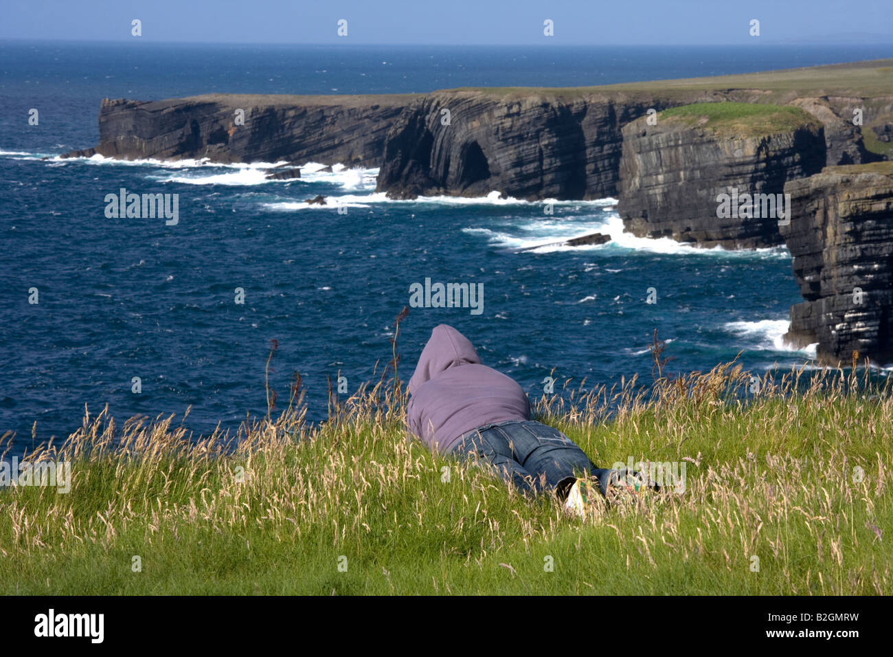Femme assise sur le bord de la falaise de Loop Head, à l'Atlantique, dans le comté de Clare, Irlande Banque D'Images