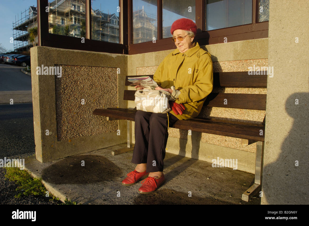 Senior woman sitting on bench in sunshine. Banque D'Images