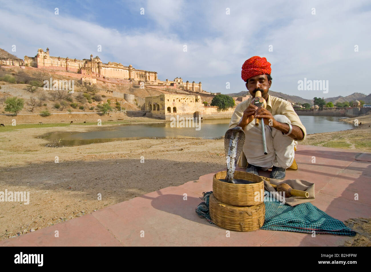 Un charmeur de serpent et son Indien ou d'ours à lunettes (Naja naja) à jouer avec le Amber Palace dans l'arrière-plan. Banque D'Images