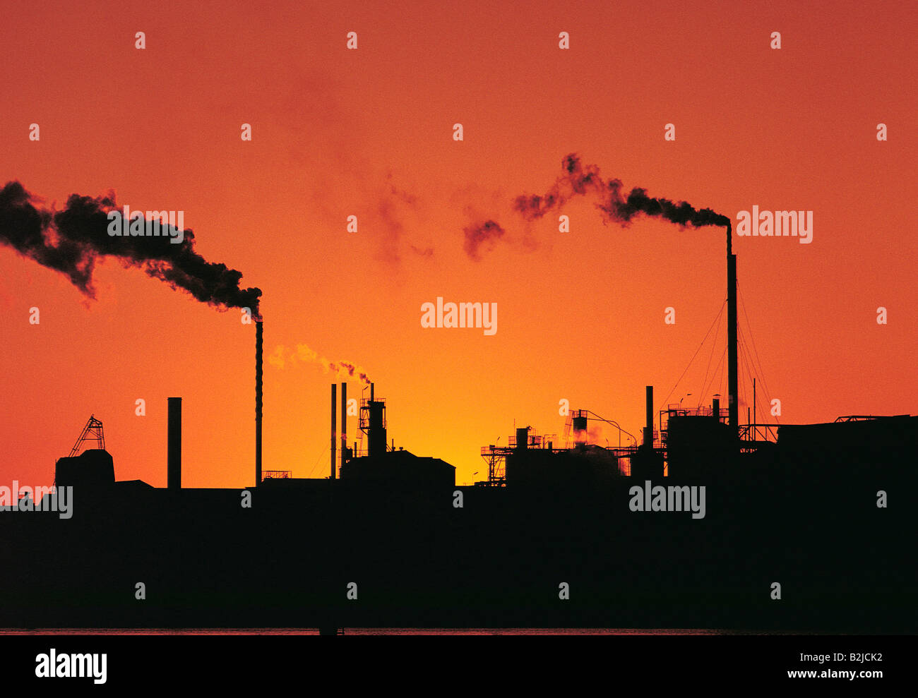 Australie. Horizon industriel. Raffinerie avec cheminées à fumer au coucher du soleil. Banque D'Images