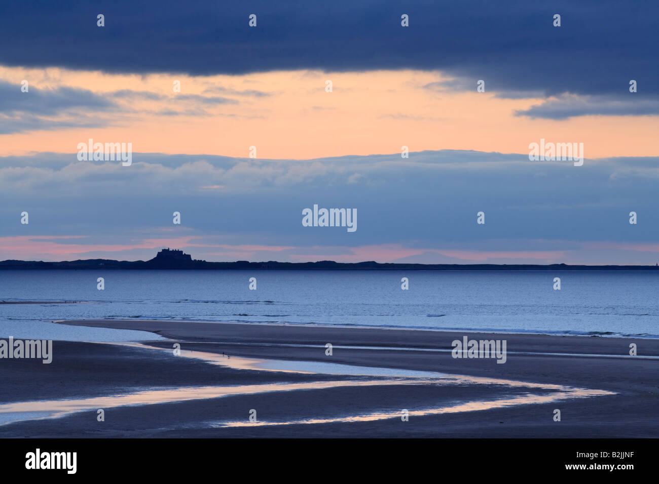 L'île de Lindisfarne (saints) silhouetté contre un coucher de soleil d'été à l'échelle de Budle Bay sur la côte de Northumbrie, Angleterre Banque D'Images