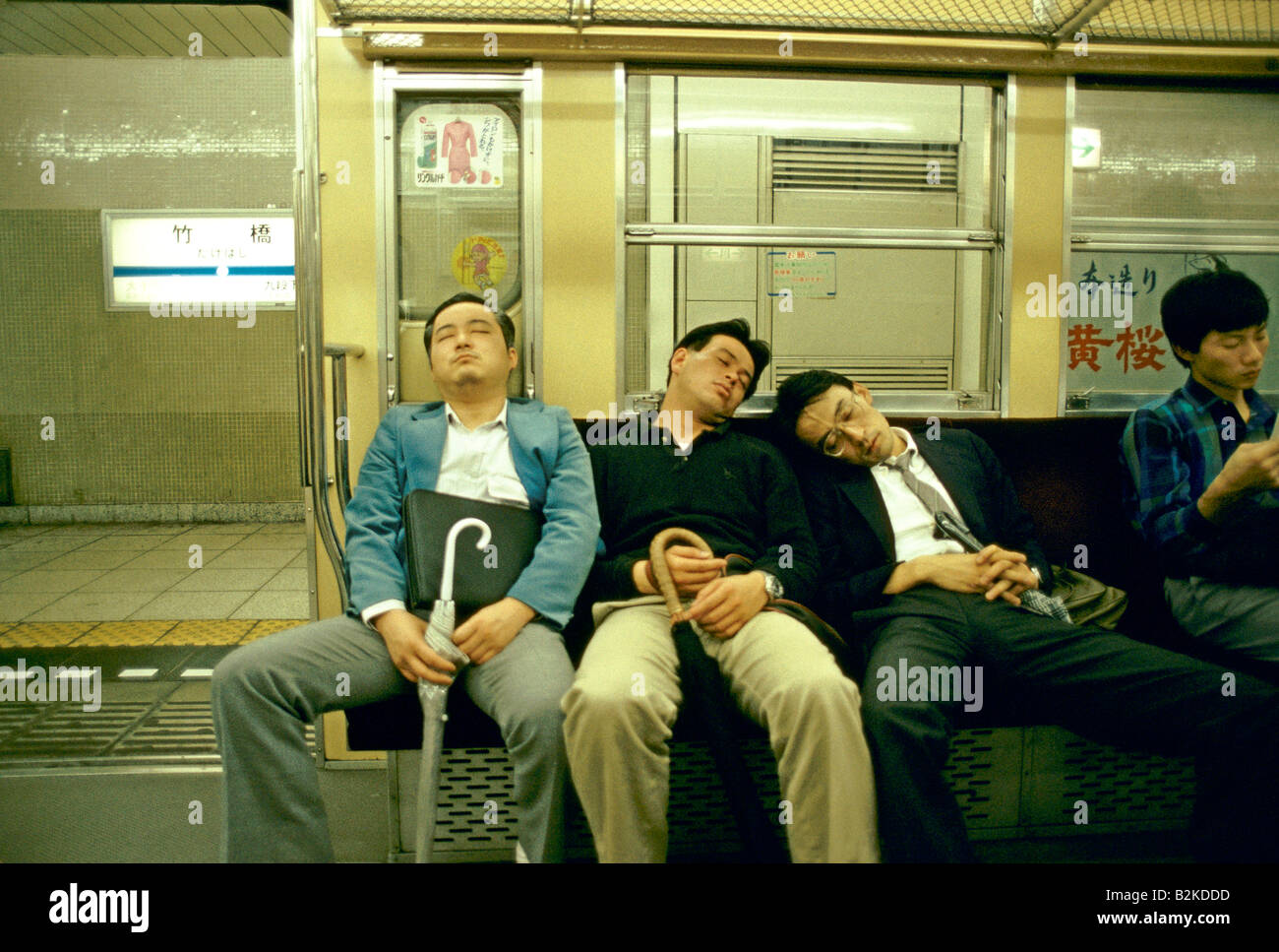 Les hommes ENDORMIS SUR UN TRAIN TOKYO JAPON Banque D'Images