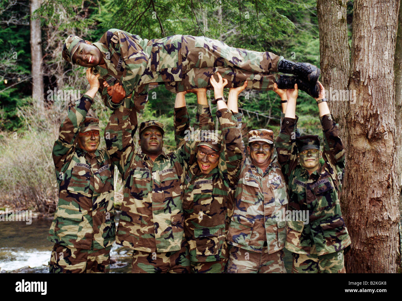 Les soldats de l'Armée US mâle tenir une femme soldat en altitude pour une photographie humoristique Banque D'Images
