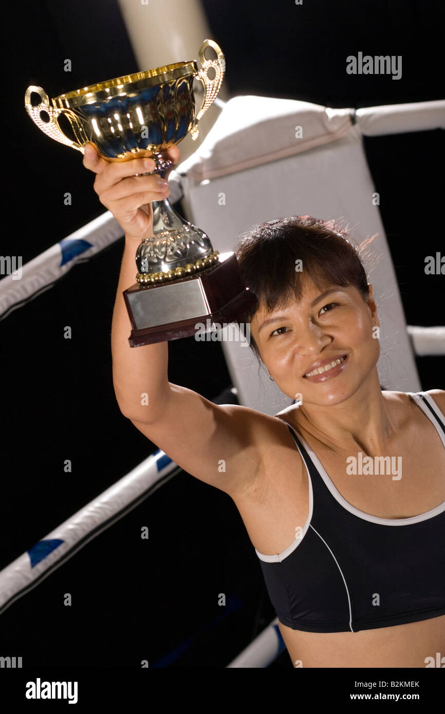 Jeune femme tenant un trophée dans un ring de boxe Banque D'Images