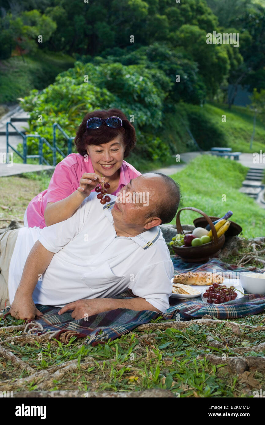 Femme mature de raisins d'alimentation a senior man à un pique-nique Banque D'Images