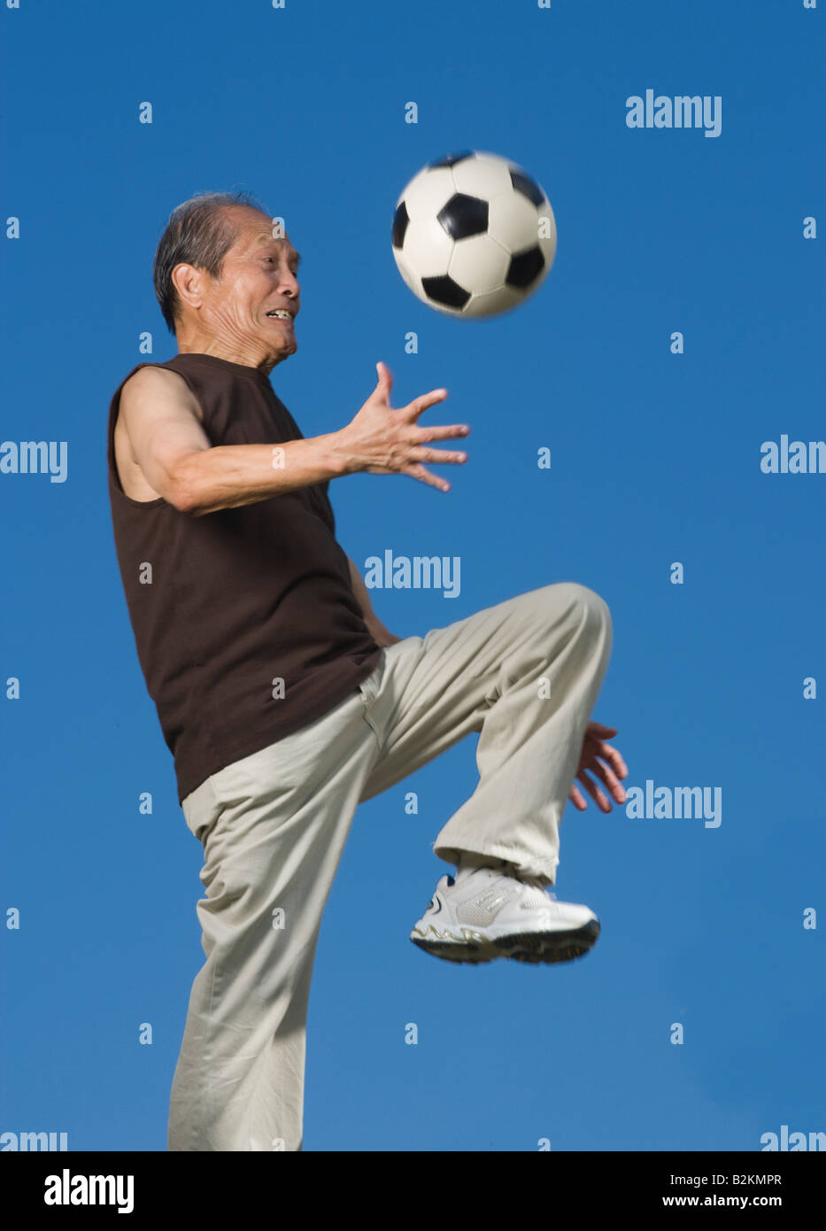 Low angle view of a senior man jouer avec un ballon de foot Banque D'Images