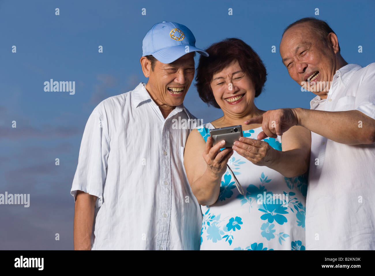 Femme mature avec deux hommes à la recherche d'un appareil photo numérique à Banque D'Images
