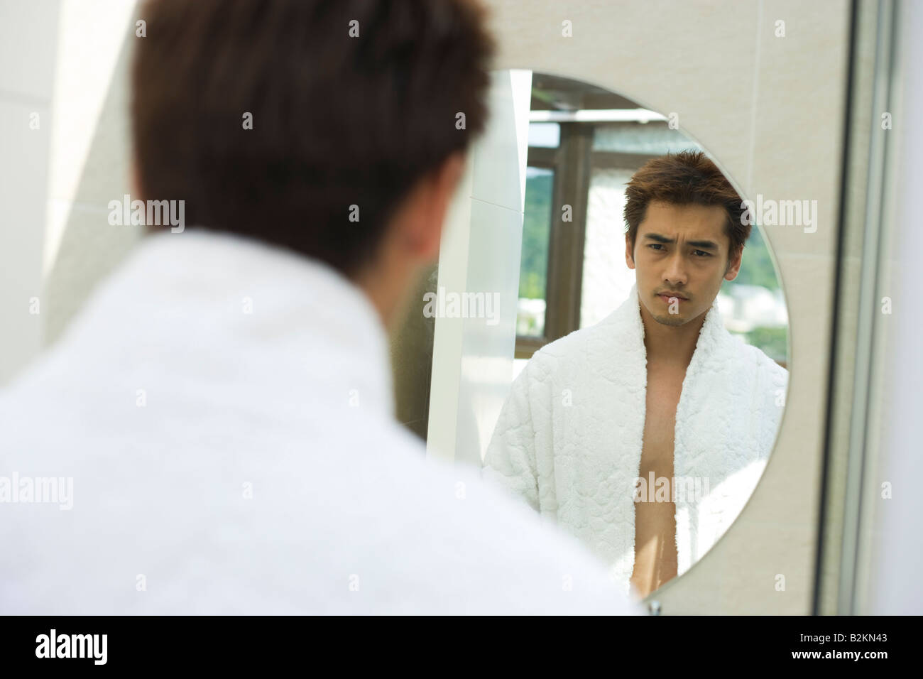 Jeune homme debout devant un miroir Banque D'Images